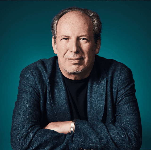 Hans Zimmer sitting and smiling with his arms crossed