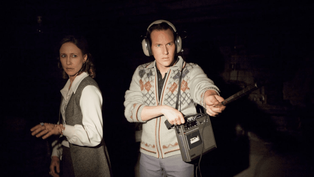 Ed Warren standing and investigating with Lorraine Warren in The Conjuring