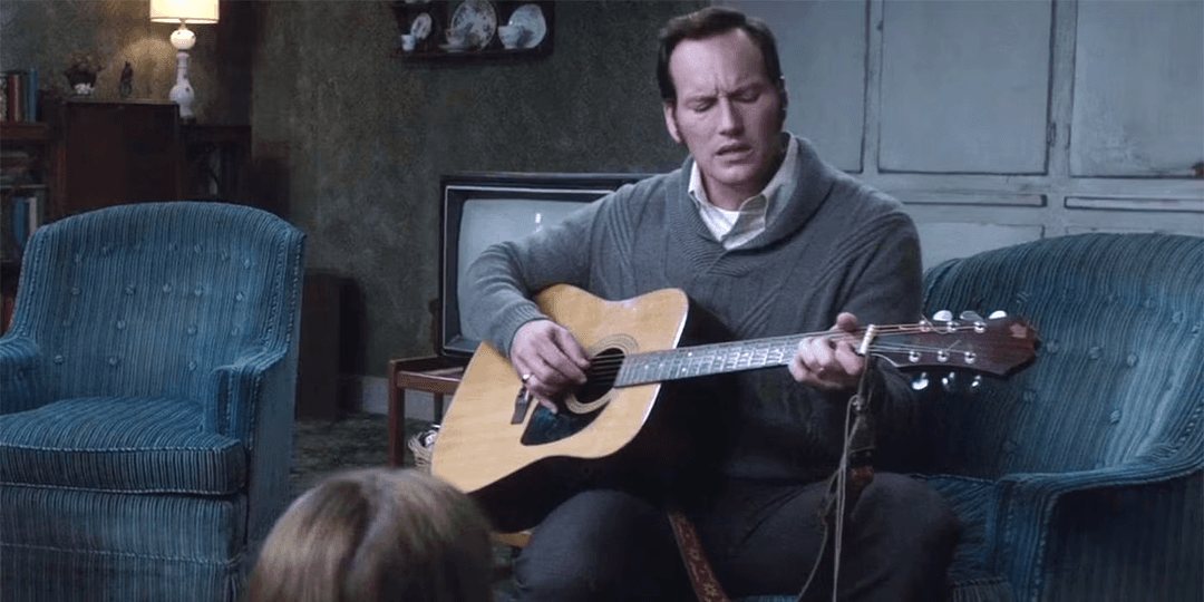 Ed Warren holding an acoustic guitar in The Conjuring 2